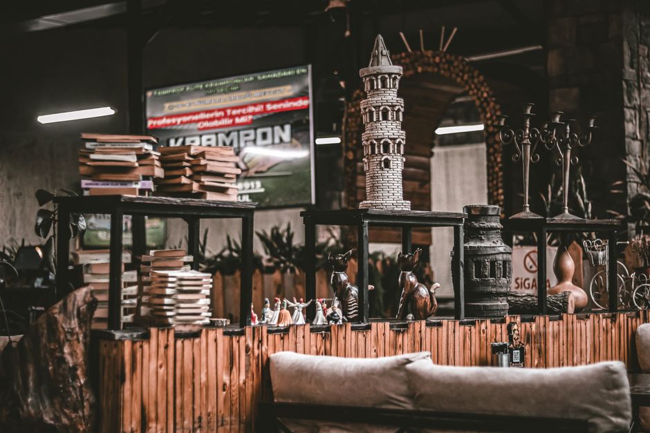 A cozy indoor library setting featuring stacked books and eclectic decor elements, creating a warm ambiance.